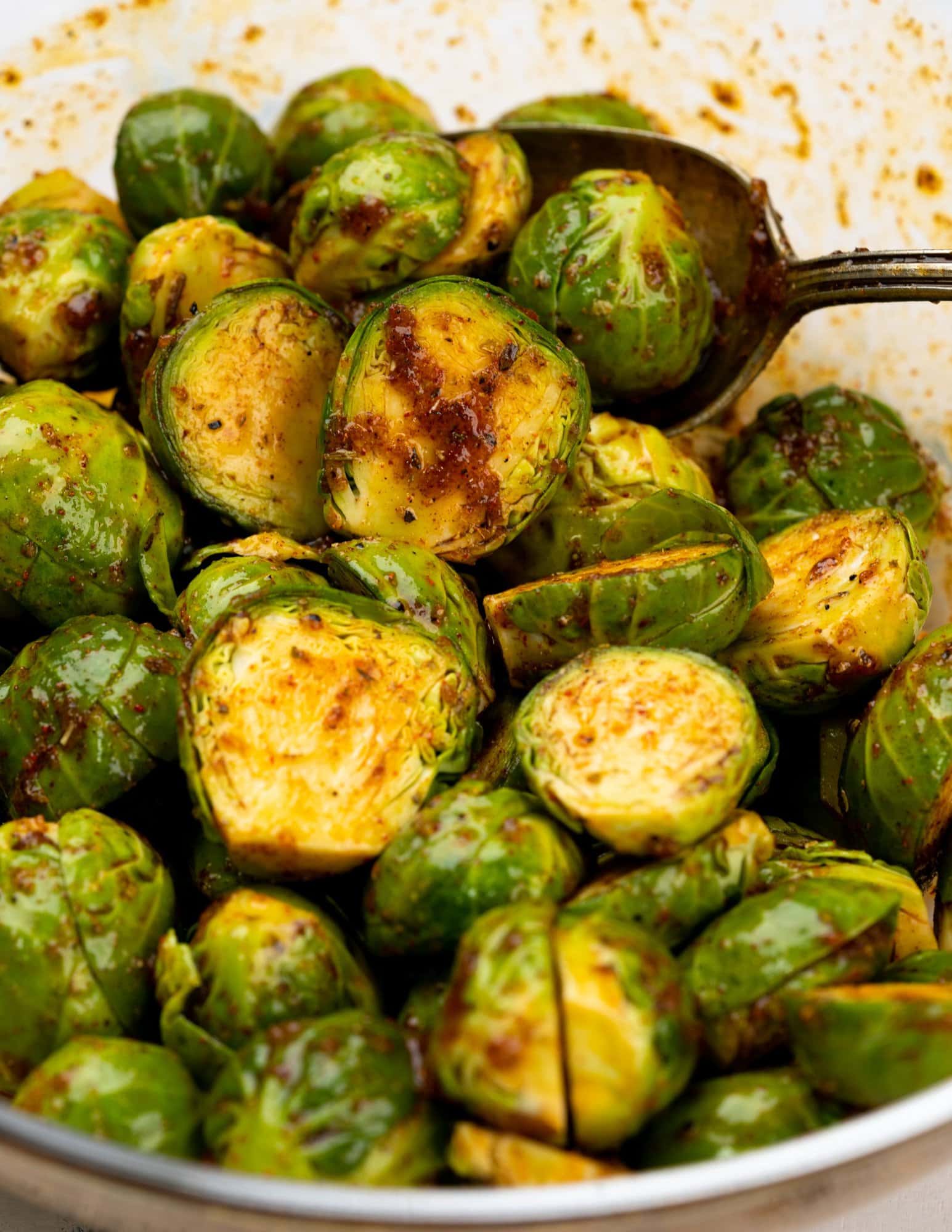 Image showing chopped brussel sprouts tossed in a bowl and coated with seasoning mix.