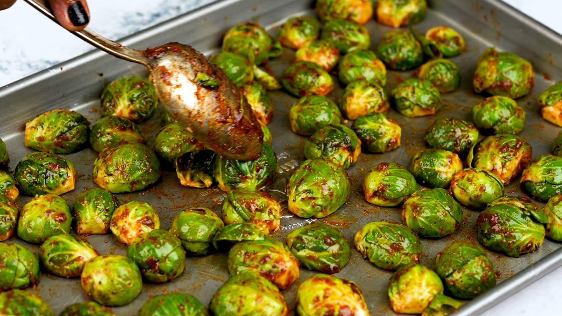 brussels sprouts are chopped, tossed with seasoning mix and arranged in the baking tray in a single layer