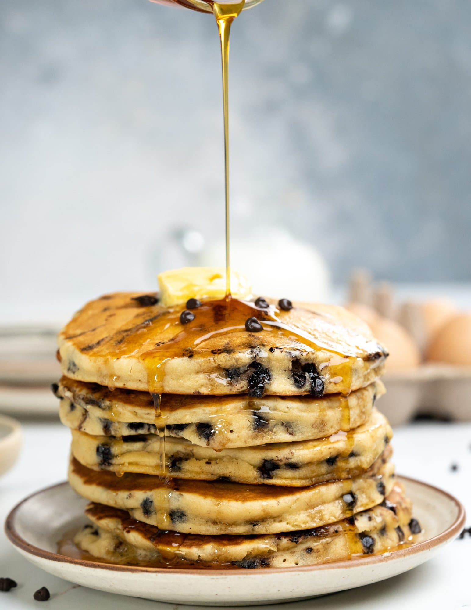Stack of fluffy chocolate chip pancakes served with maple syrup and butter. 