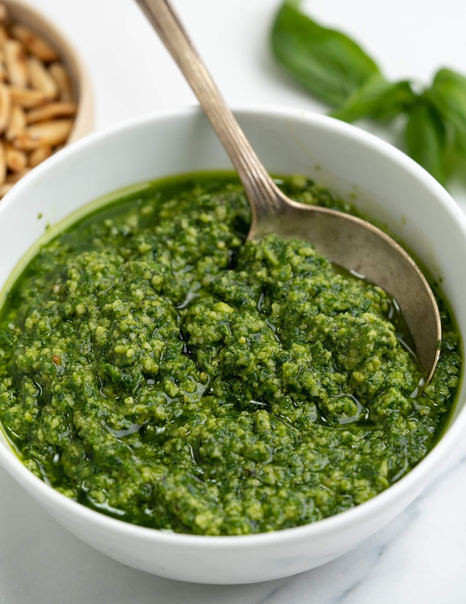 Fresh and vibrant pesto with a slightly coarse texture served in a white bowl.