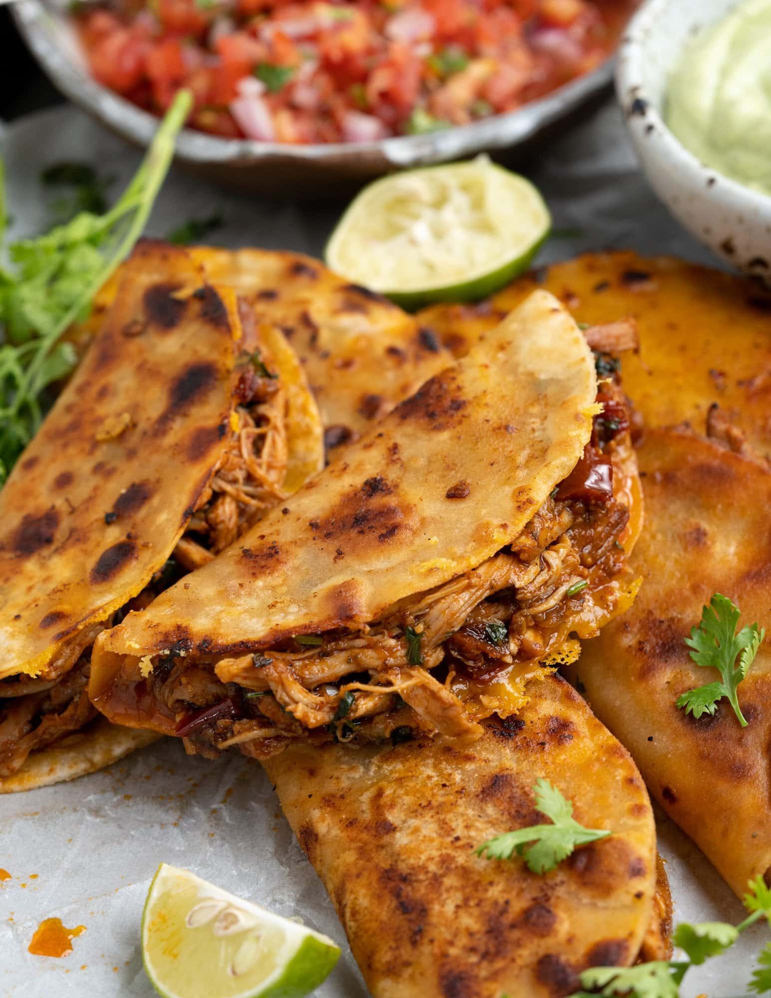 A stack of homemade chicken tacos showing fried tortillas filled with juicy shredded chicken and Mexican cheese.