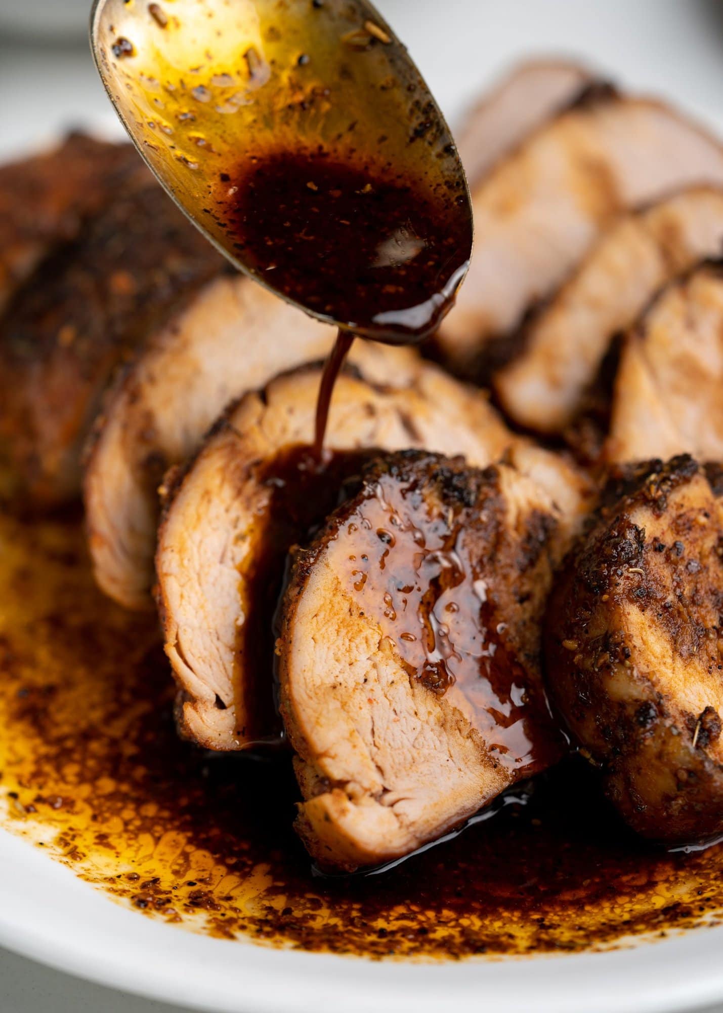Dripping sauce over the stacked pork tenderloin slices.