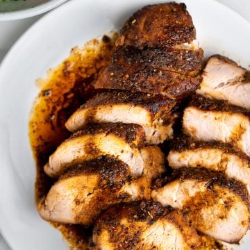 Horizontal stack of pork tenderloin slices show a seared crust and tender meat inside.