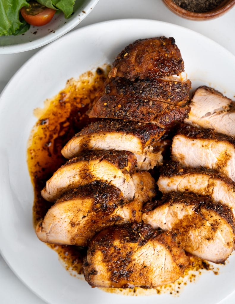 Horizontal stack of pork tenderloin slices show a seared crust and tender meat inside.