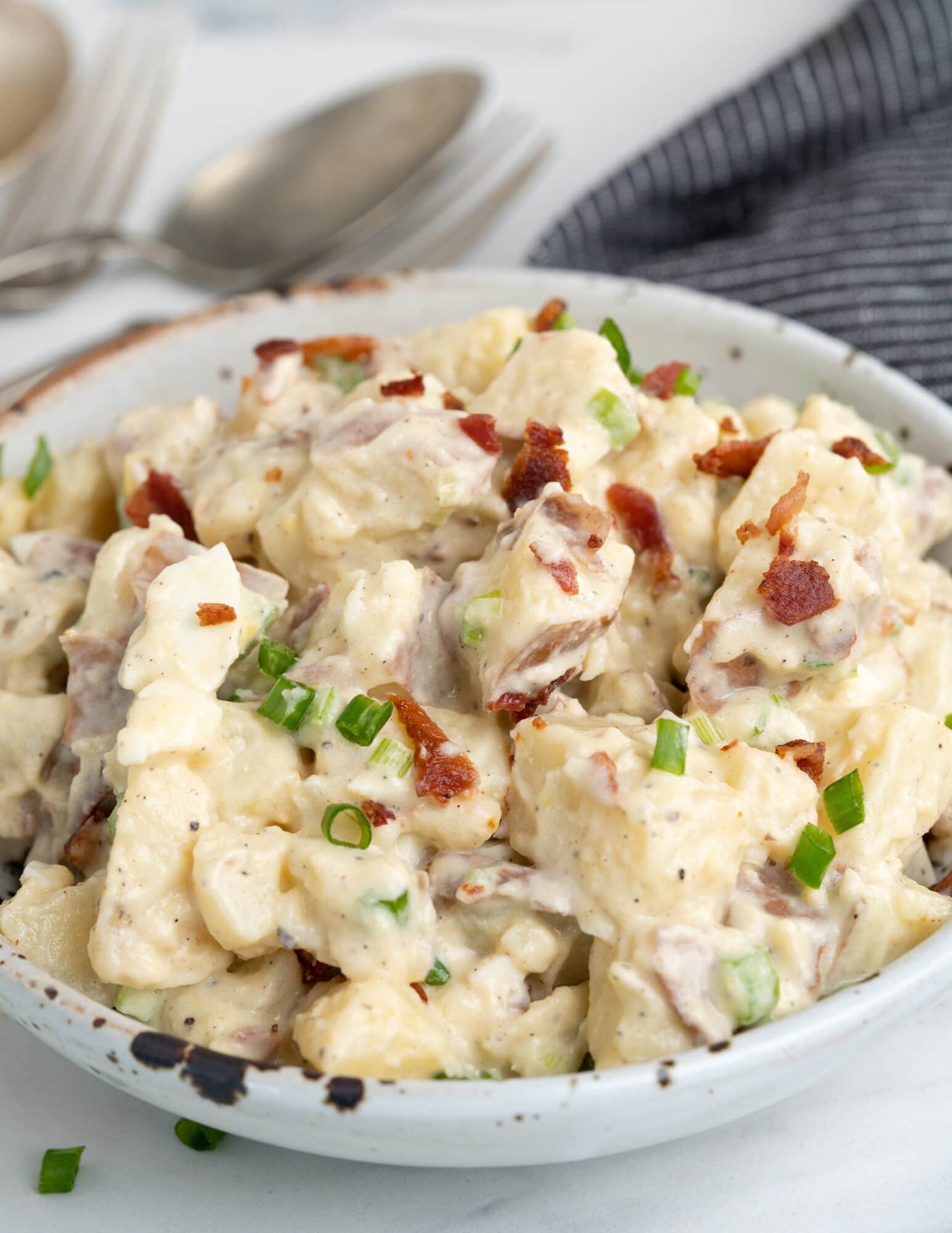 Creamy Potato salad made with red-skinned potatoes, mayo-based dressing, and topped with bacon is one of the best side dishes for BBQs, potlucks etc.