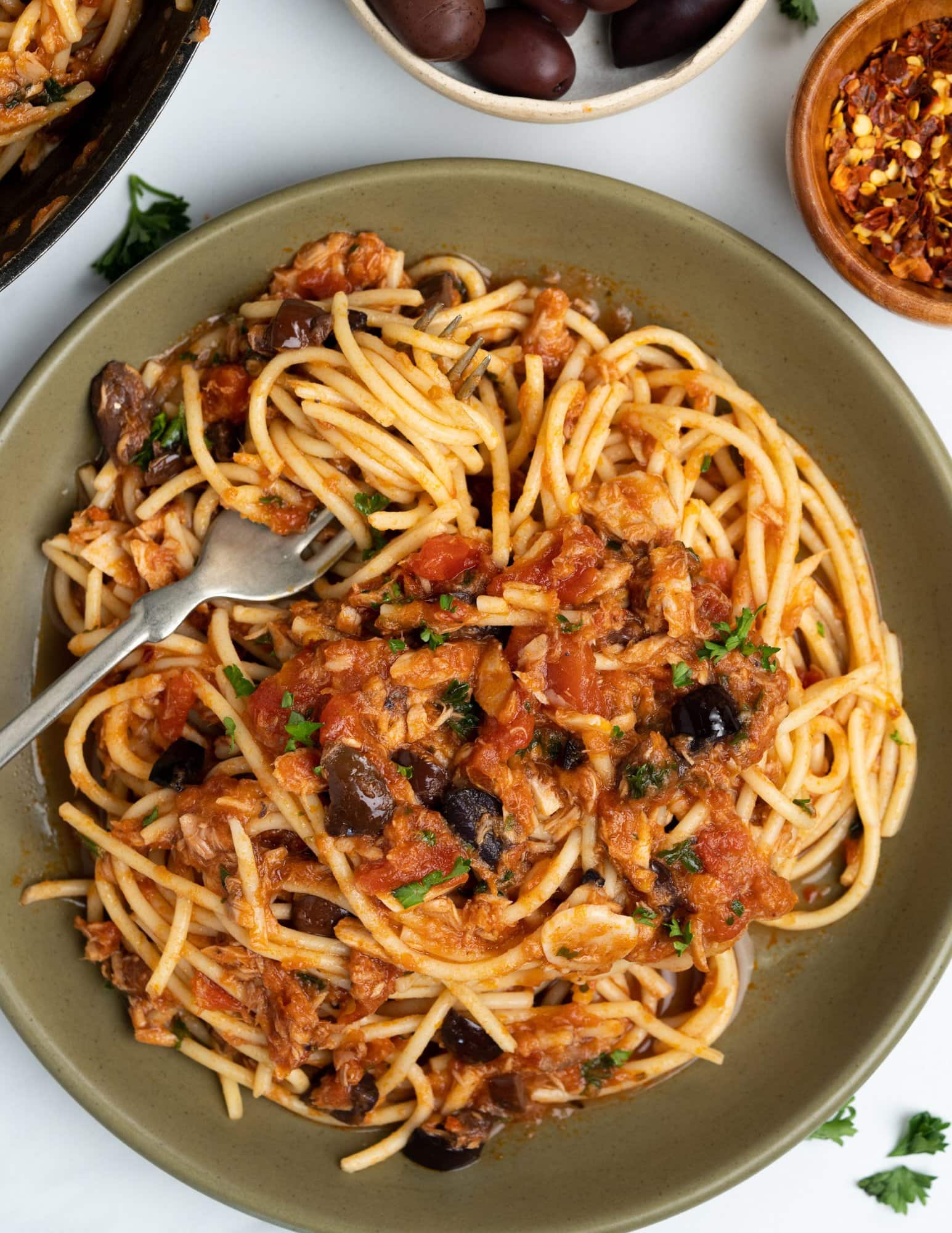 Tomato tuna pasta with Spaghetti, tomato and tuna sauce with olives and seasonings, garnished with parsley.