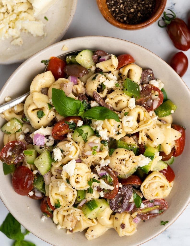 Top shot of tortellini pasta salad made with feta cheese sprinkled and mixed with greek salad dressing.