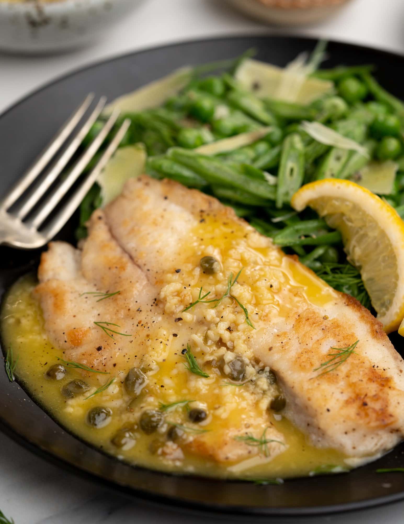 Plate of crispy fried Tilapia served with Lemon Caper sauce and a side of salad. 