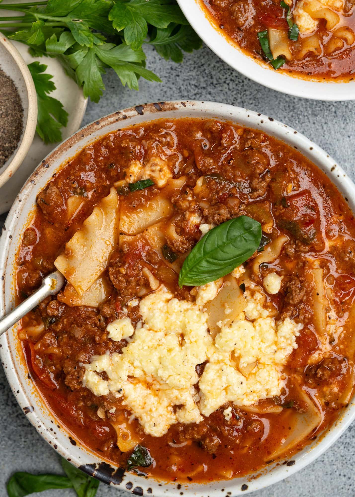 Lasagna soup served in a bowl topped with cheese mixture. 