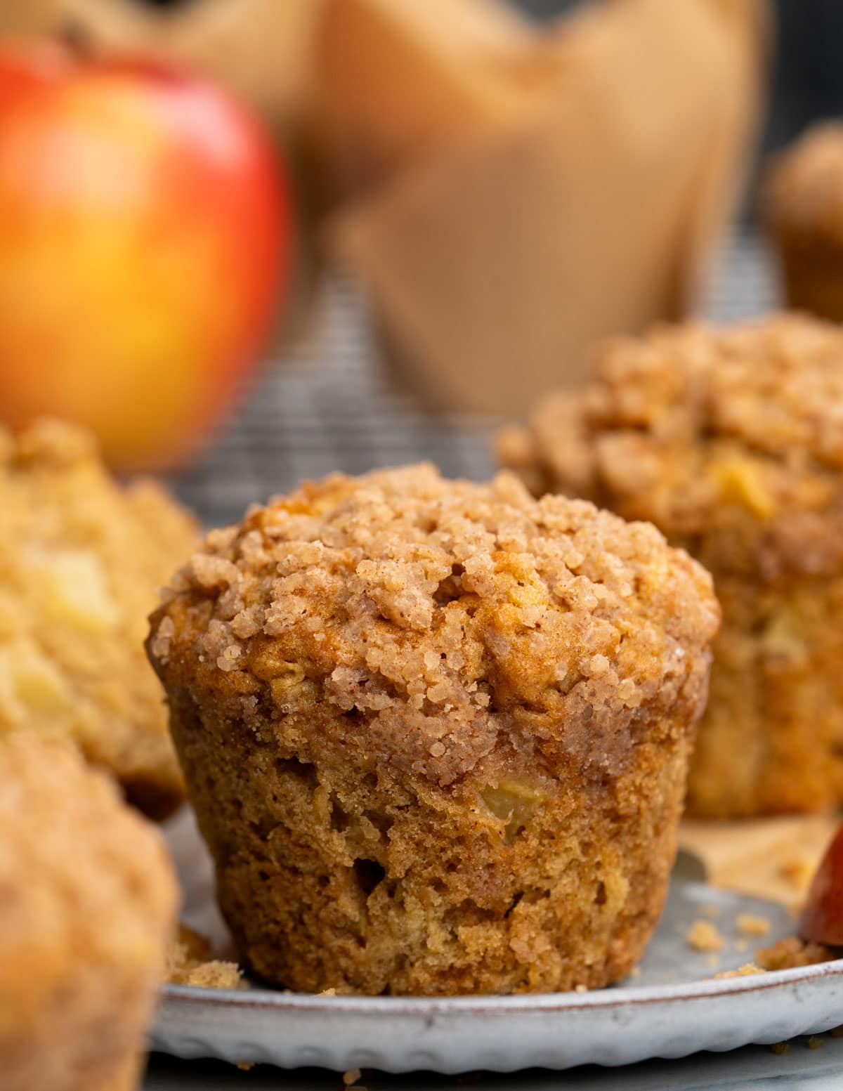Tall Cinnamon apple muffin with crunchy cinnamon sugar topping. You can notice a chunk of apple on the side of the muffin.