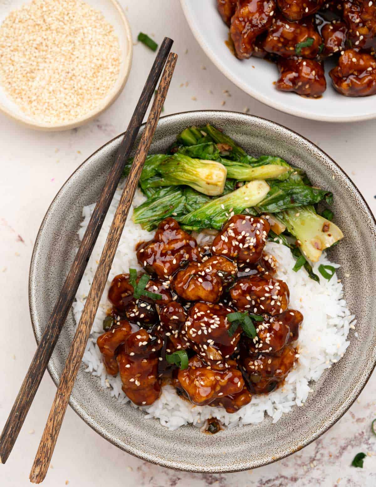 Top view of honey sesame chicken on a bowl of rice. 