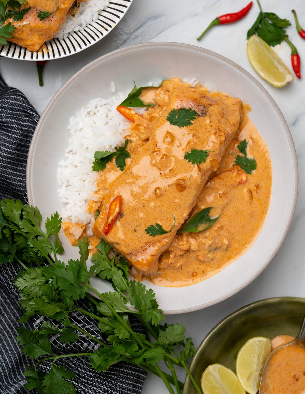Creamy coconut salmon curry served on a bed of white steamed rice, in a white bowl.