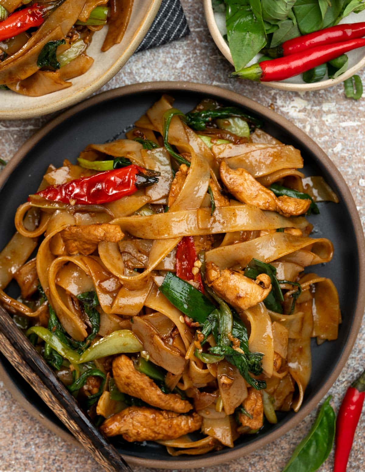 Close up view of Spice Drunken Noodles ( Pad Kee Mao) with juicy chicken, birds eye chilies and Thai basil.