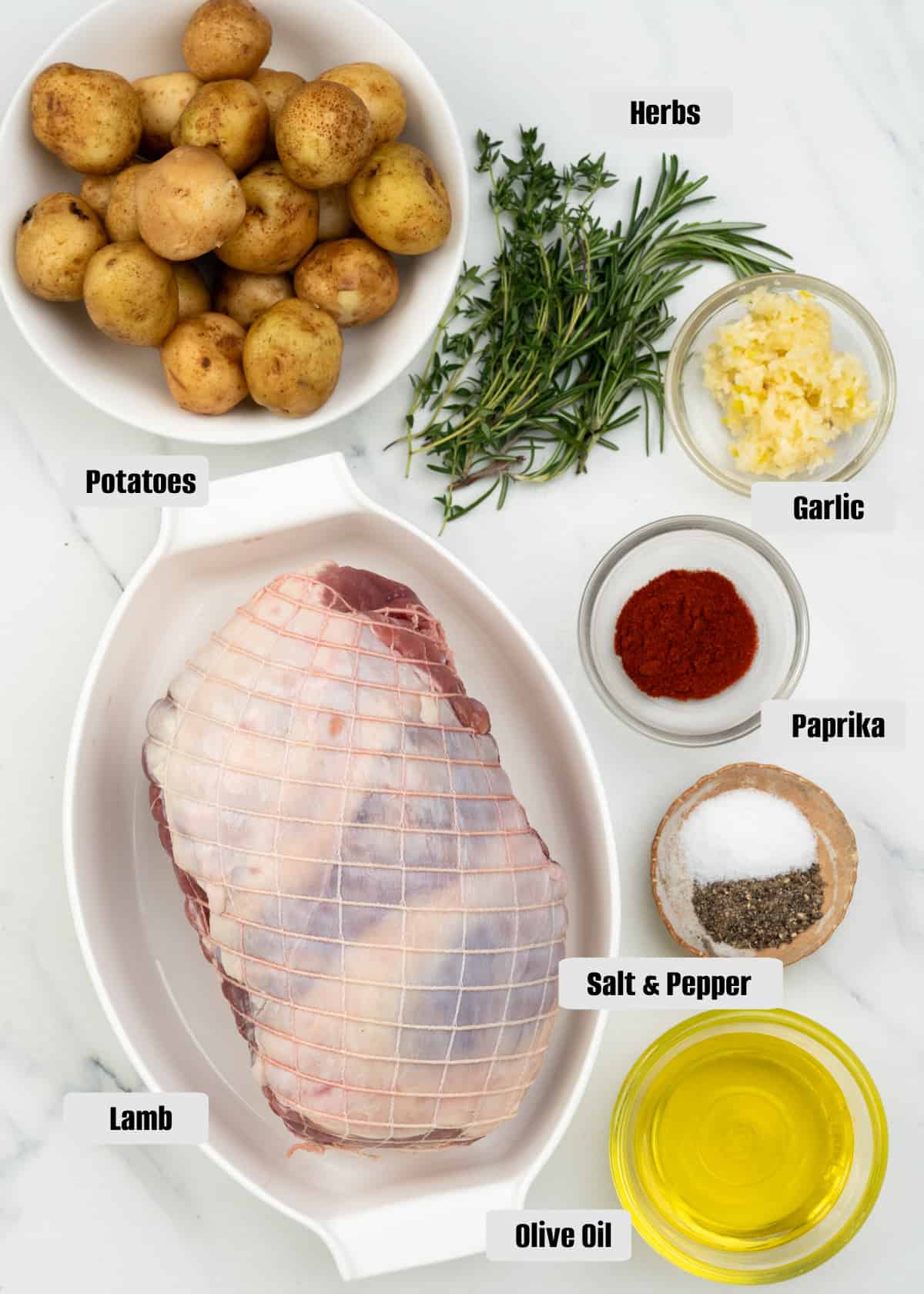 Ingredients like boneless lamb shoulder, potatoes, garlic, herbs, paprika, salt, pepper, and olive oil.