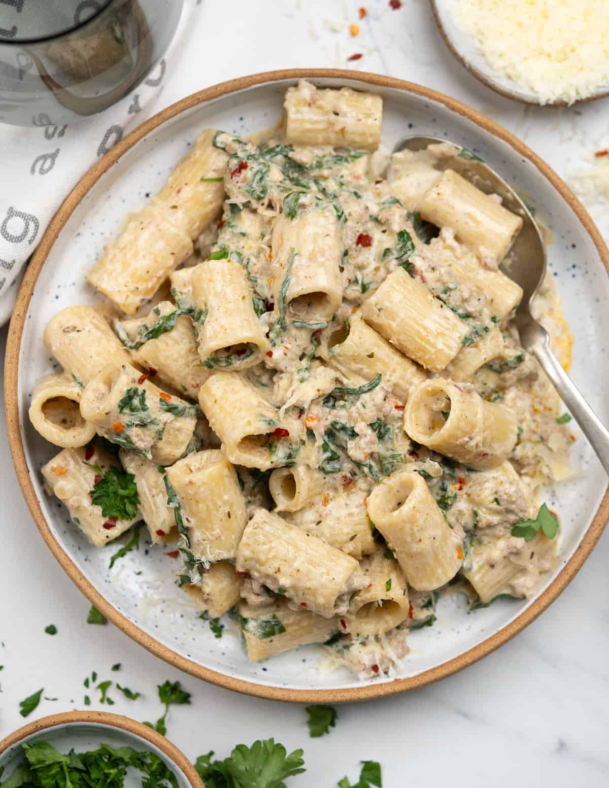 Plate of rigatoni pasta with creamy spinach sausage sauce. 