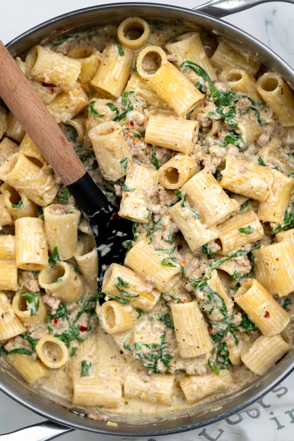Rigatoni pasta in a creamy spinach and ground sausage sauce