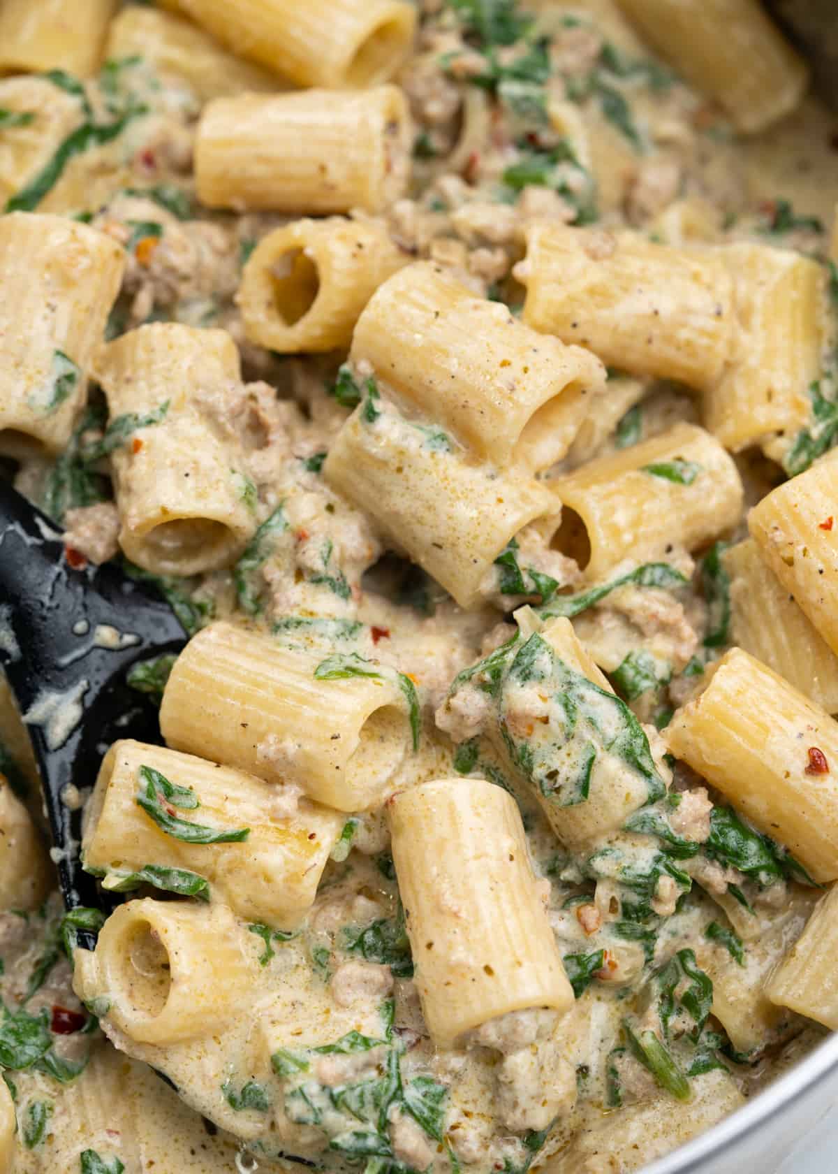Rigatoni pasta in a creamy spinach and ground sausage sauce