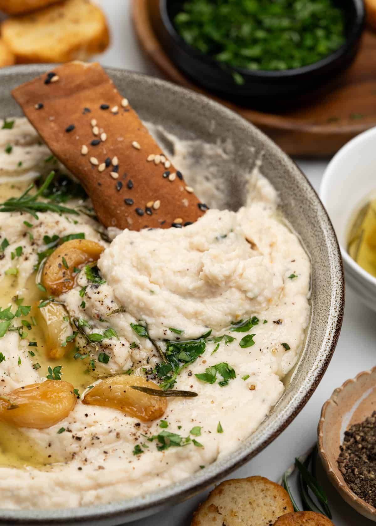 Image of plated white bean dip topped with roasted garlic olive oil served with 