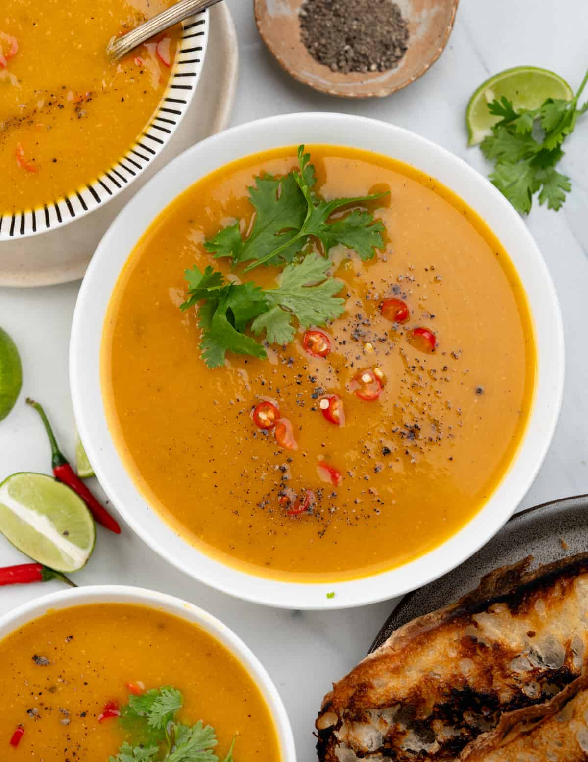 Thai pumpkin soup with coconut milk. Garnished with fresh cilantro and chopped red chillies. 