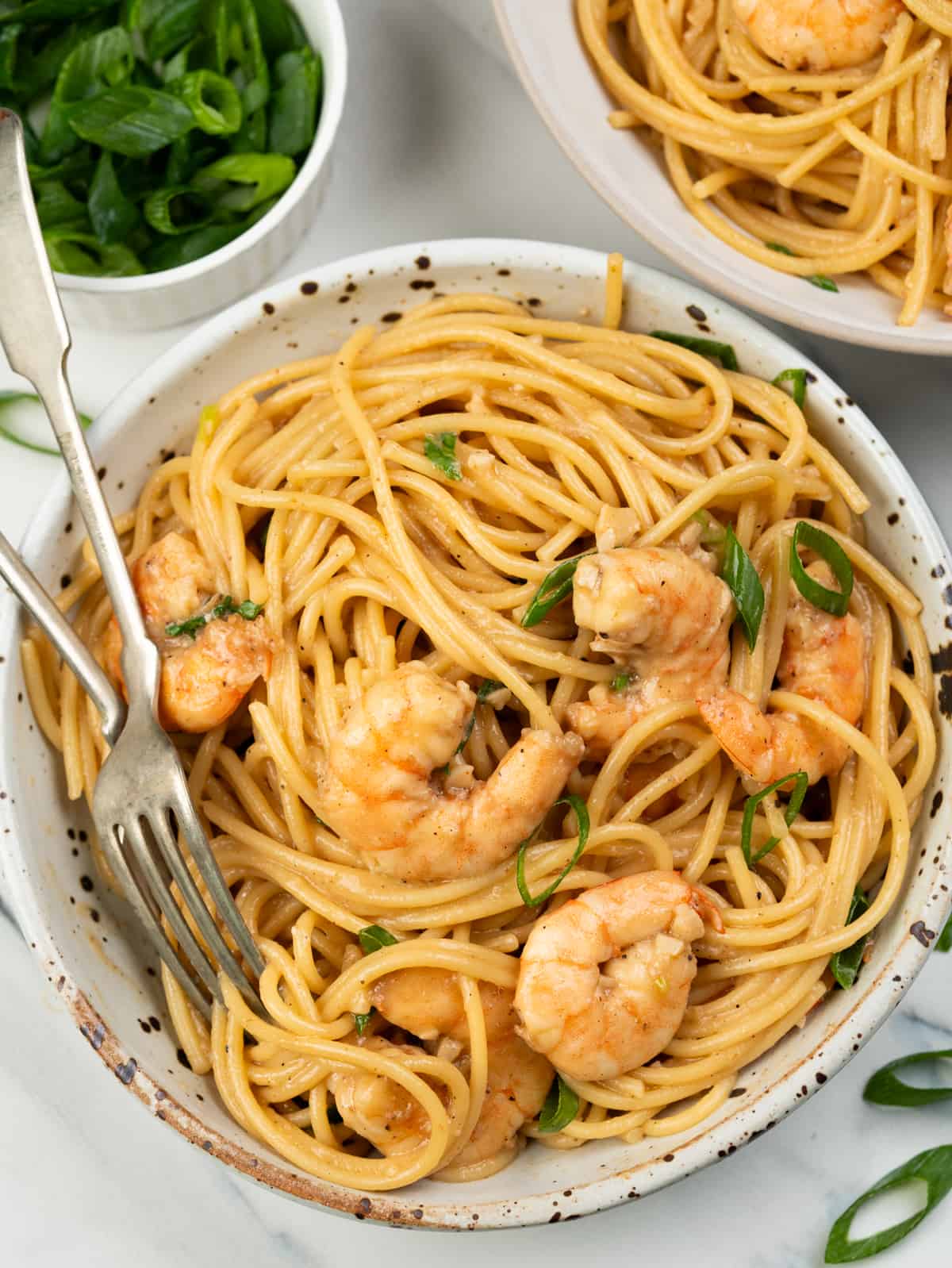 Bowl of Garlic shrimp noodles in Asian inspired butter sauce, juicy shrimps and green onion.