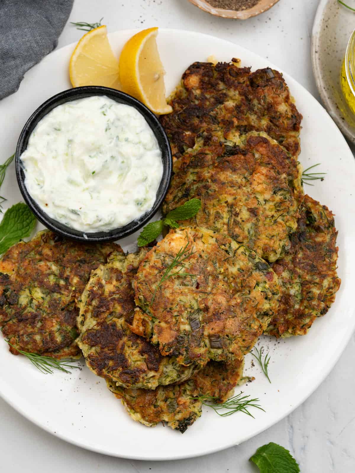 plate of Greek style Zucchini fritters served with tzatziki dip and lemon wedges