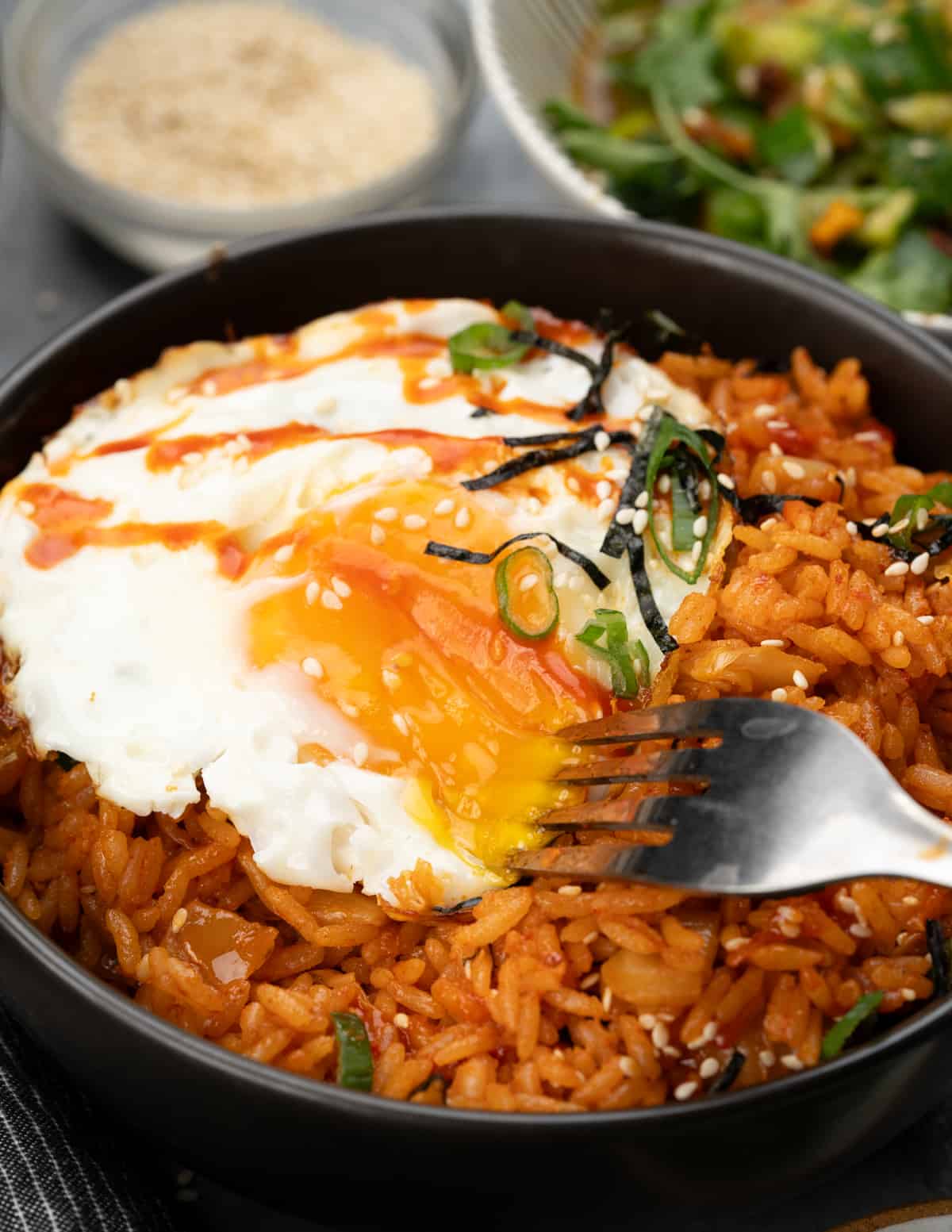 Kimchi fried rice topped with crispy sunny side up, seaweed strips, green onion and sesame seeds.