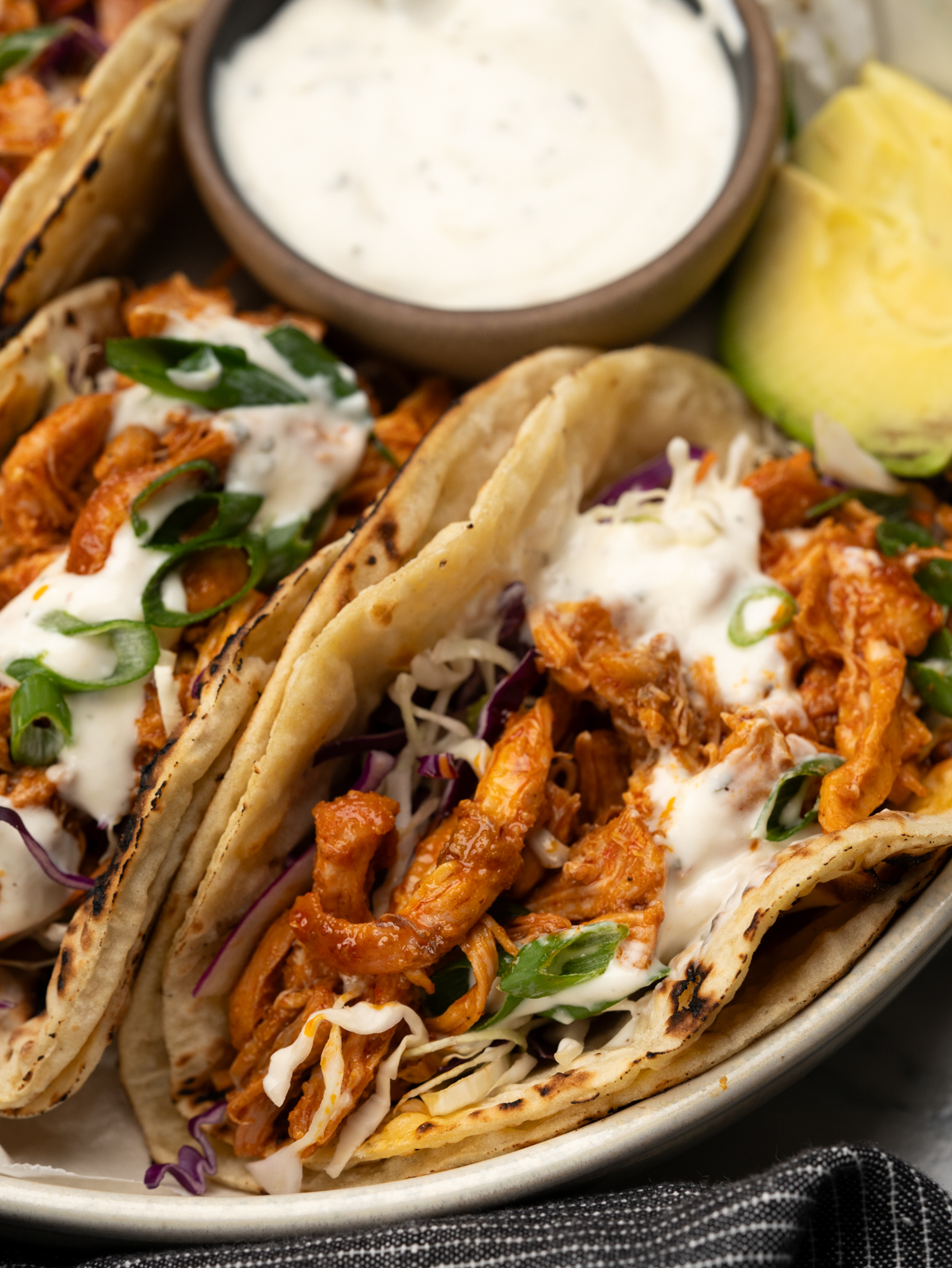 Delicious buffalo chicken tacos topped with ranch dressing and green onions