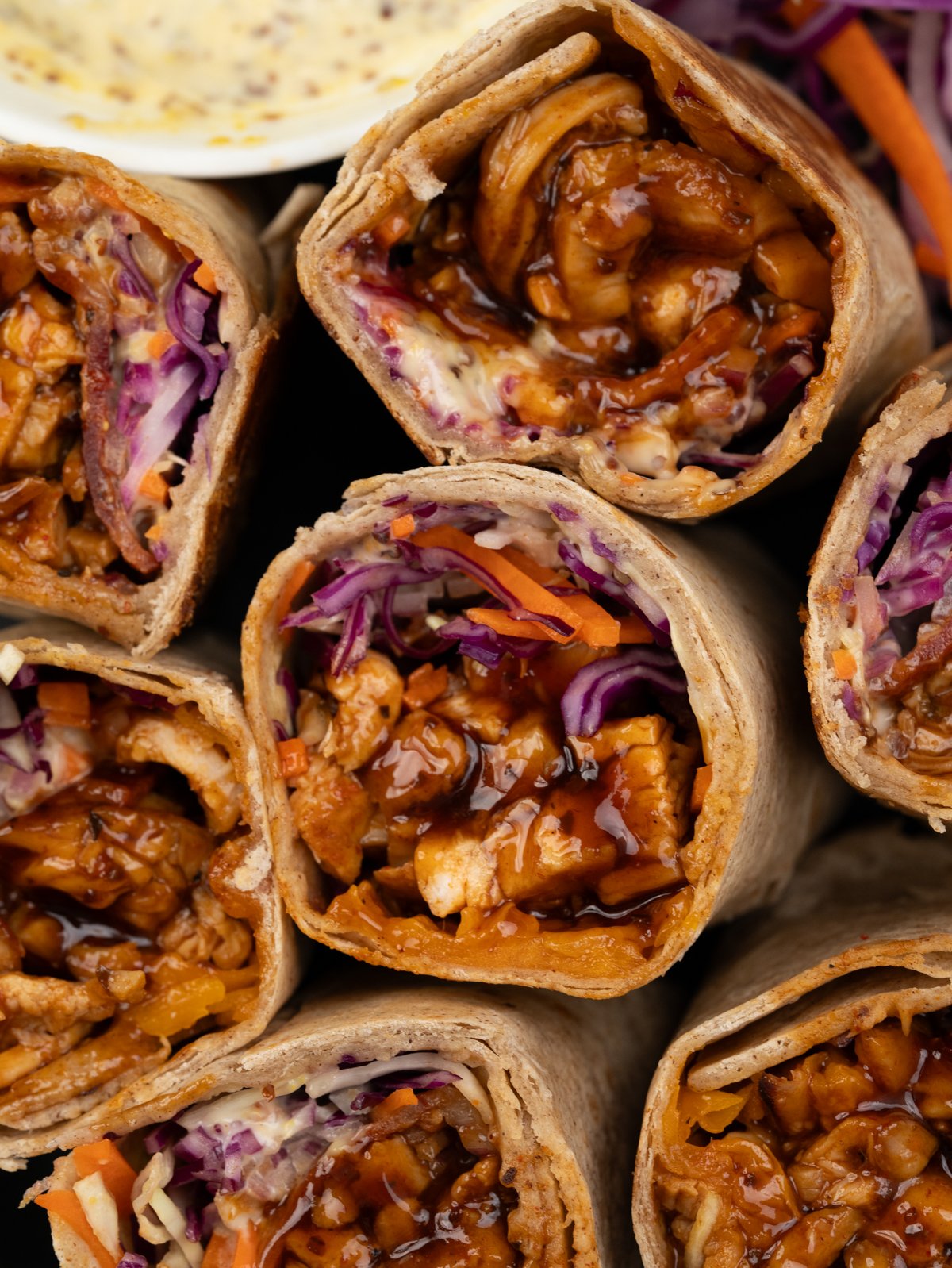 Close up of BBQ chicken wrapWITH JUICY BBQ chicken, coleslaw, cheese and bacon.