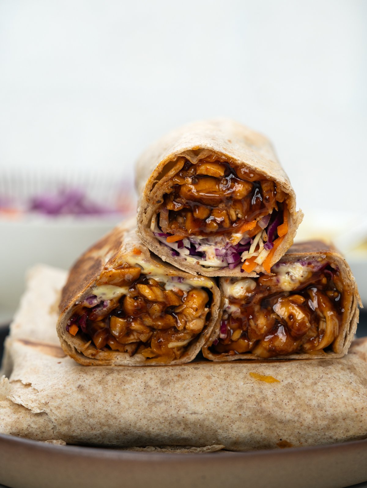 Close up of BBQ chicken wrapWITH JUICY BBQ chicken, coleslaw, cheese and bacon wrapped in a trotilla
