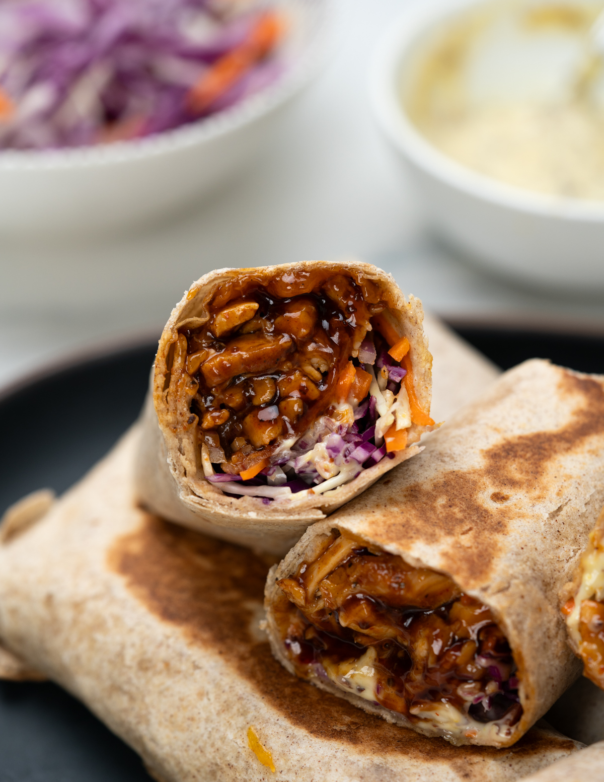 Close up of BBQ chicken wrapWITH JUICY BBQ chicken, coleslaw, cheese and bacon wrapped in a trotilla