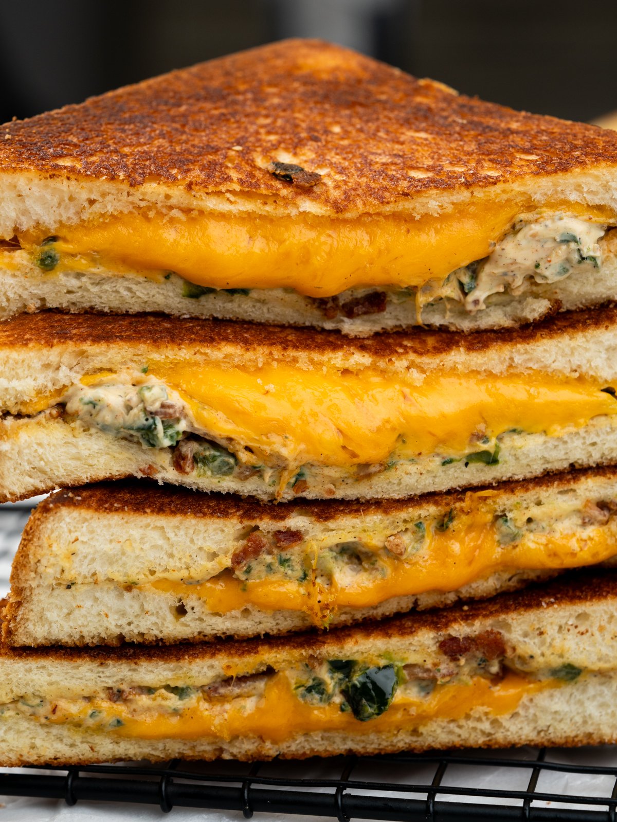 An image of a Jalapeno Popper Grilled Cheese sandwich with melted cheddar oozing out.