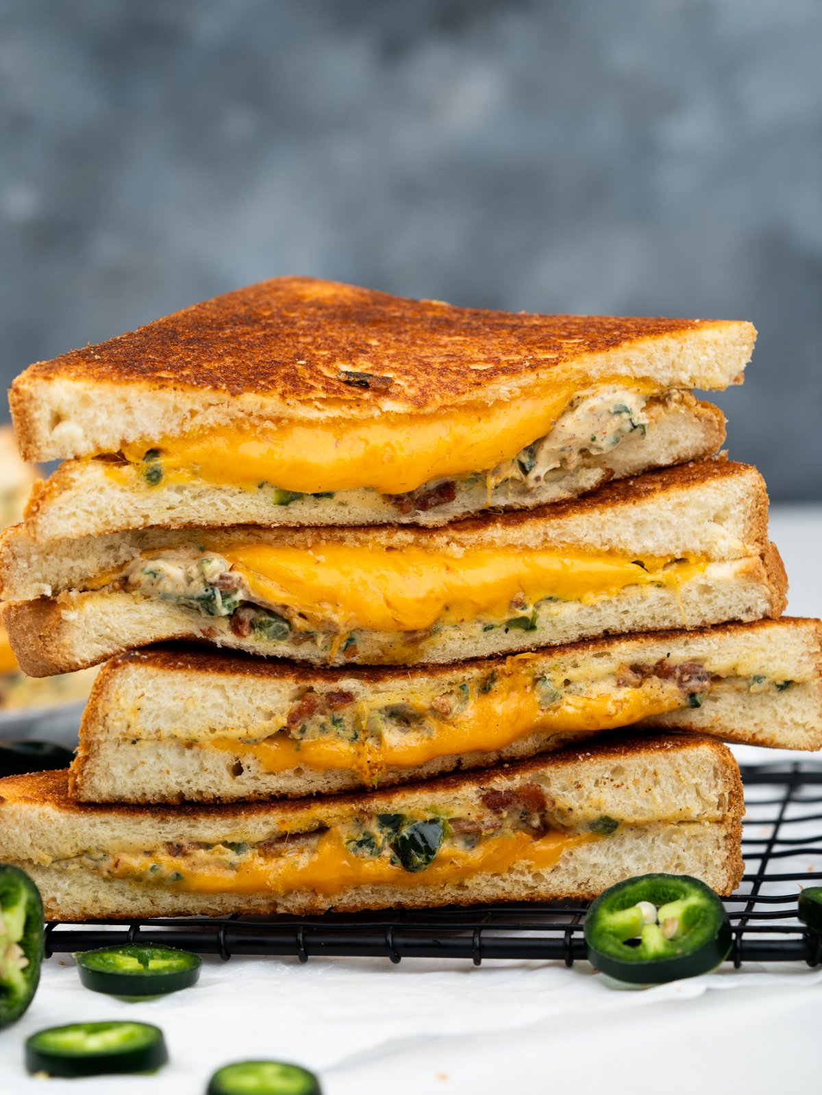 A stack of Grilled Jalapeno popper sandwiches with cheese oozing out. 