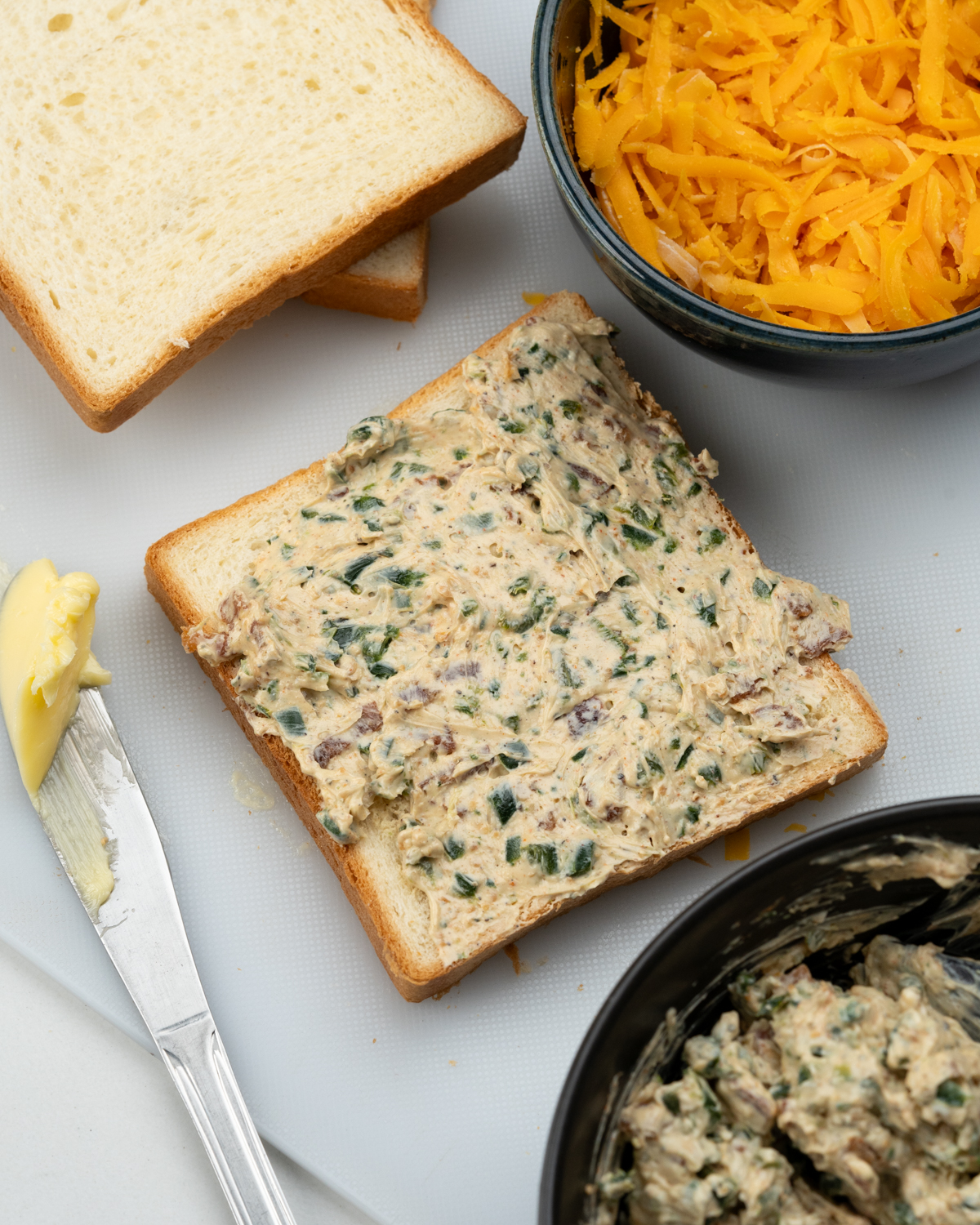 Cream cheese and roasted jalapeno filling spread on a buttered slice of bread.