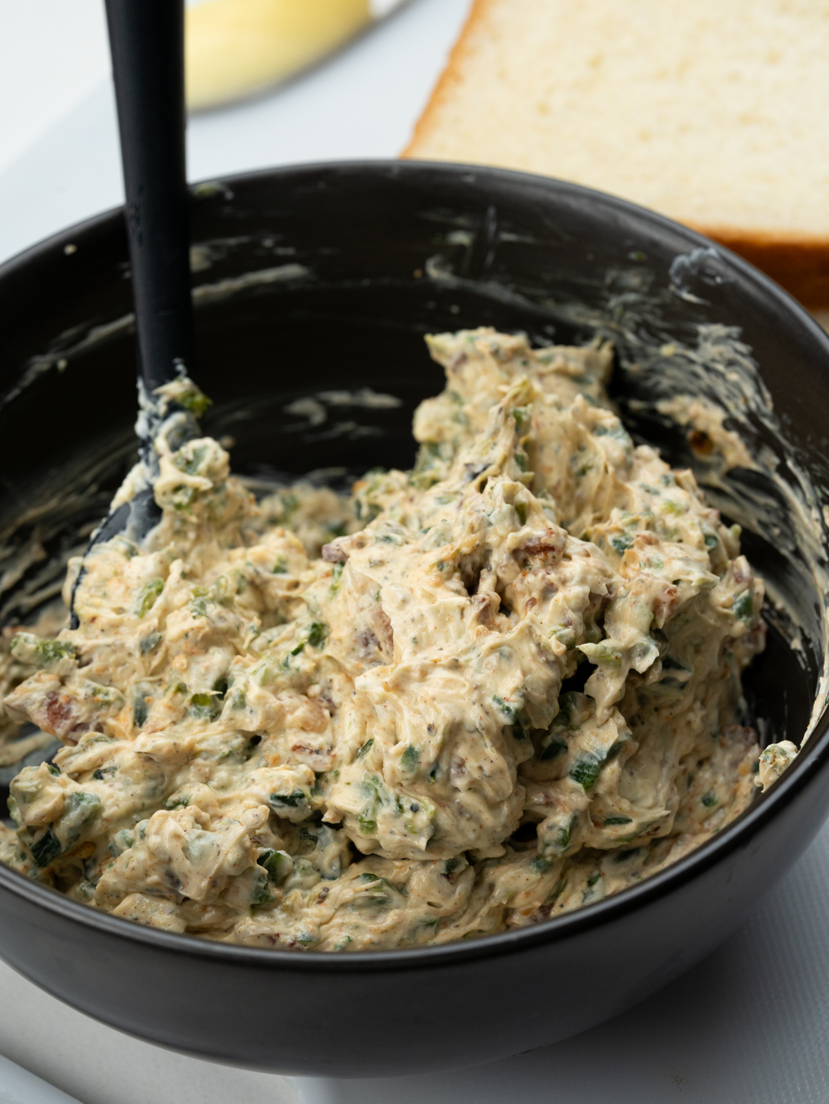 A bowl of softened cream cheese - roasted jalapeno mixture.