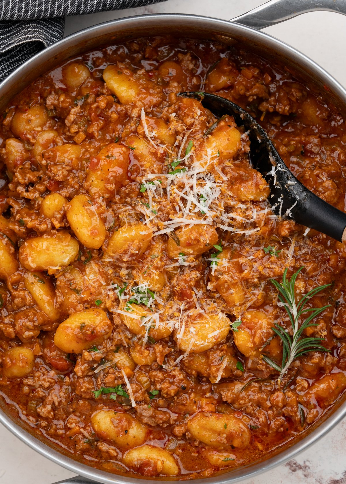 Gnocchi Bolognese in a serving dish, garnished with grated parmesan and chopped parsley. 