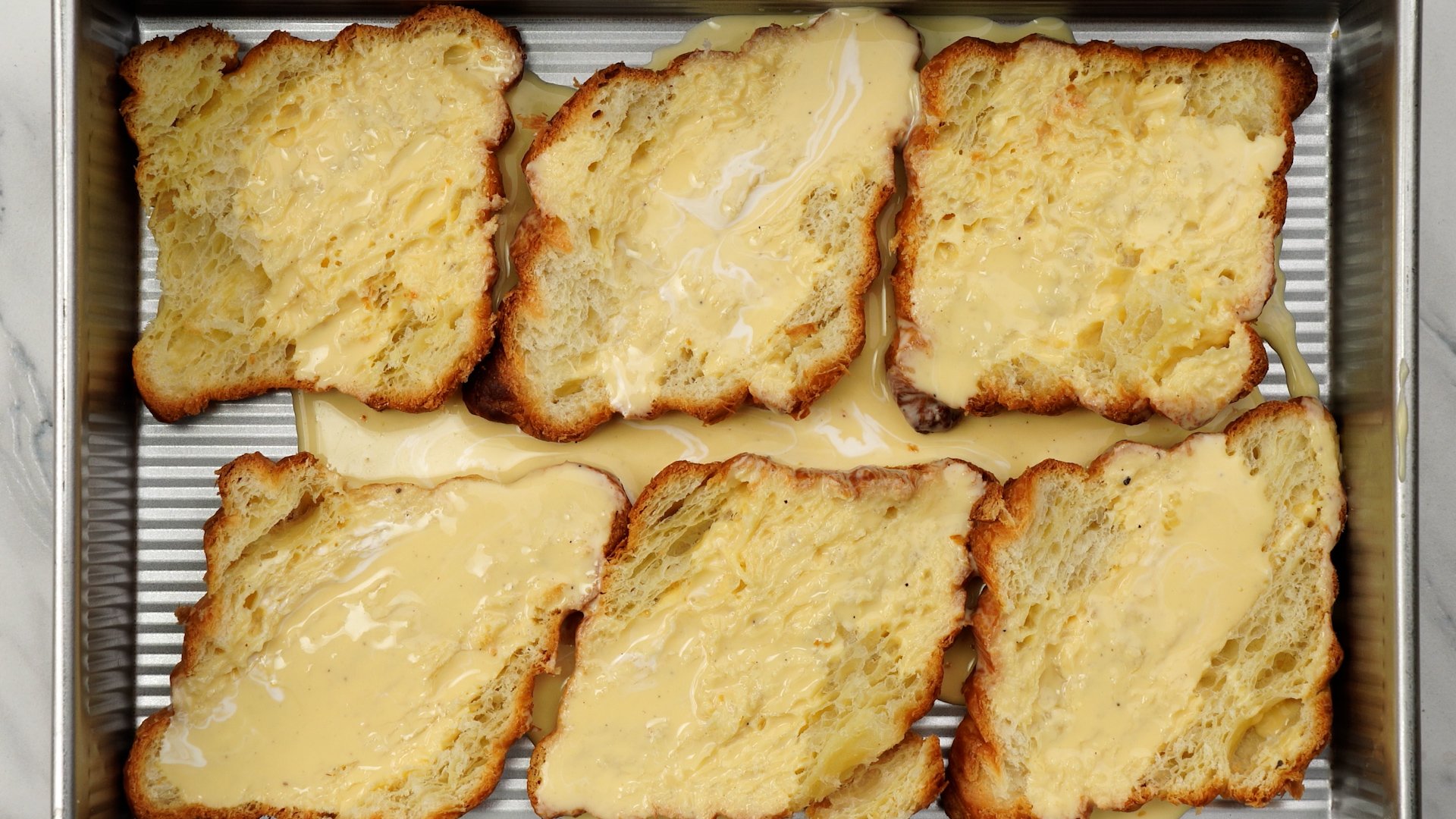 Egg-milk mix poured over halved croissants.