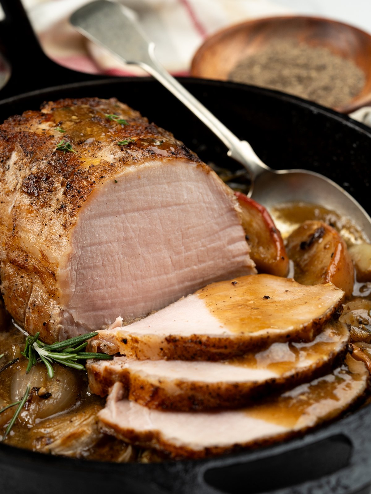 Carved slices of baked pork loin with apple sauce spooned over