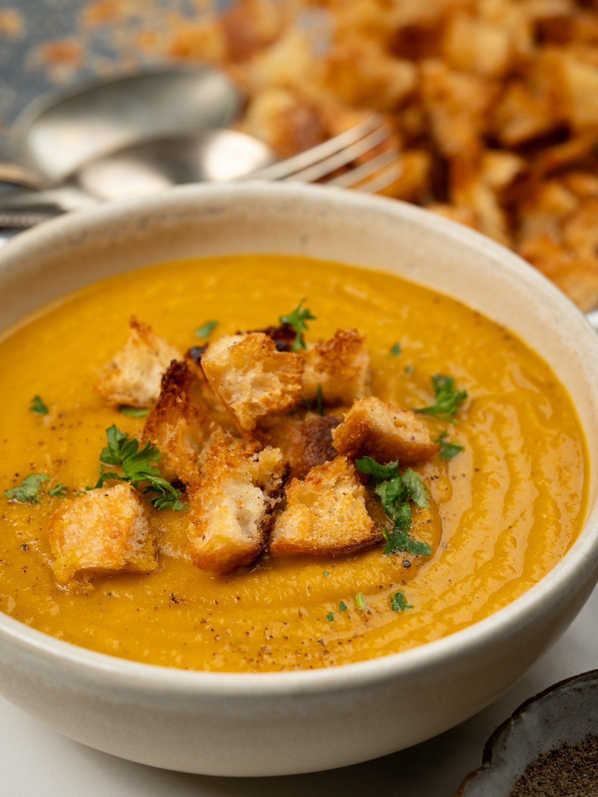 Bowl of carrot ginger soup topped with croutons. 