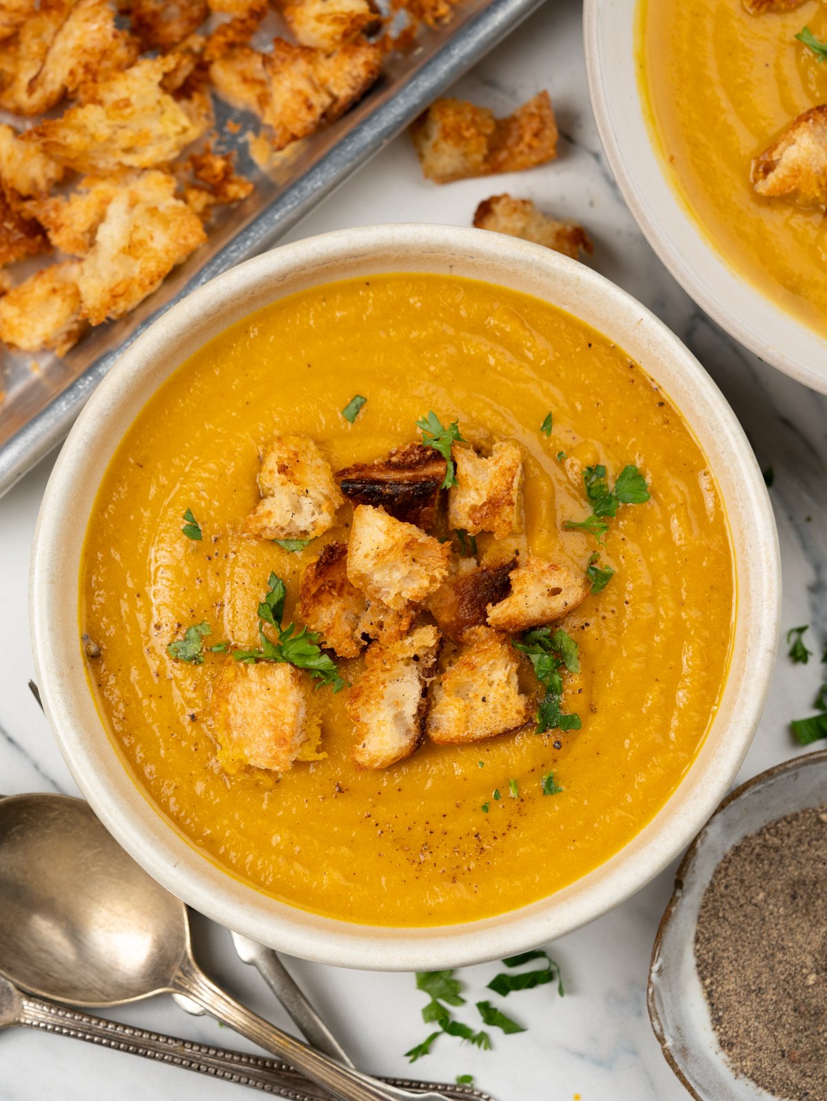 Bowl of carrot soup topped with crispy bread croutons.