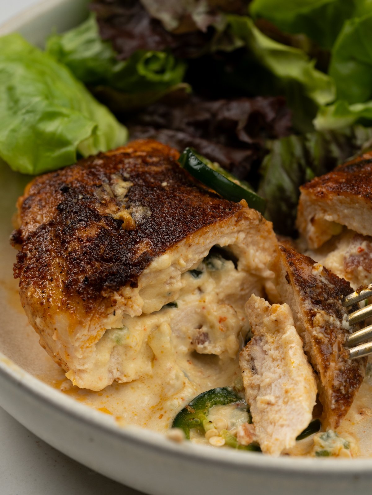 Half cut jalapeno popper stuffed chicken breast served with green salad
