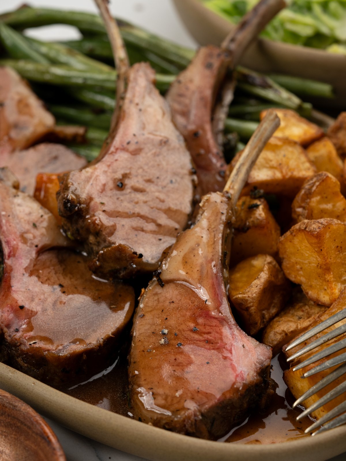 Carved lamb chops from a rack of lamb and served with gravy.